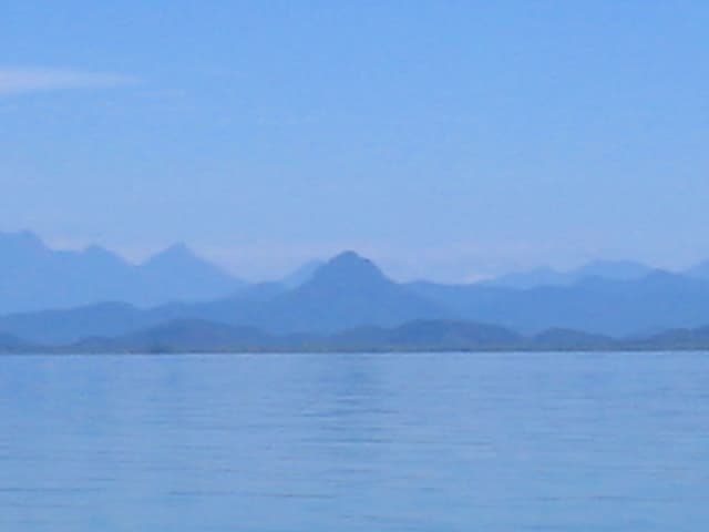 Águas espelhadas do estuário de Guaraqueçaba refletindo a cadeia montanhosa