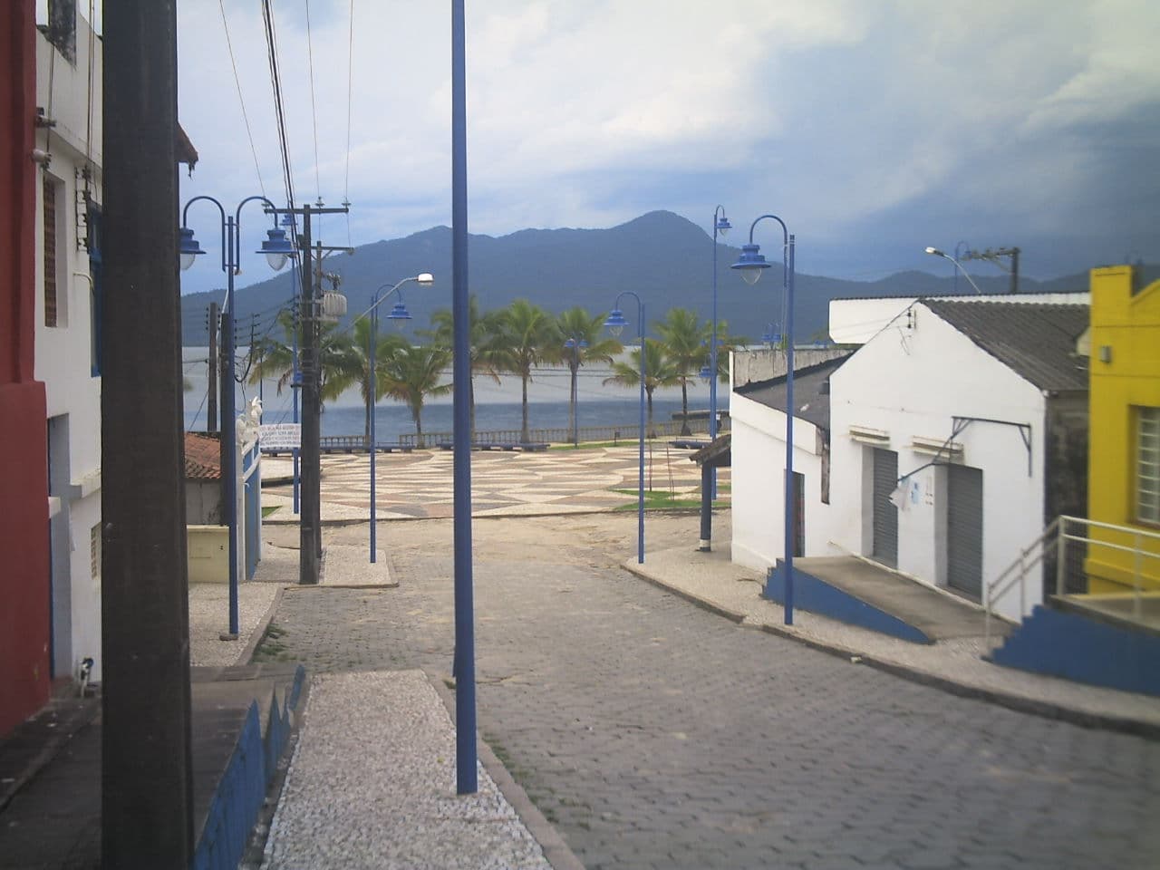 Rua histórica em declive com palmeiras, calçamento de pedras e casas coloniais