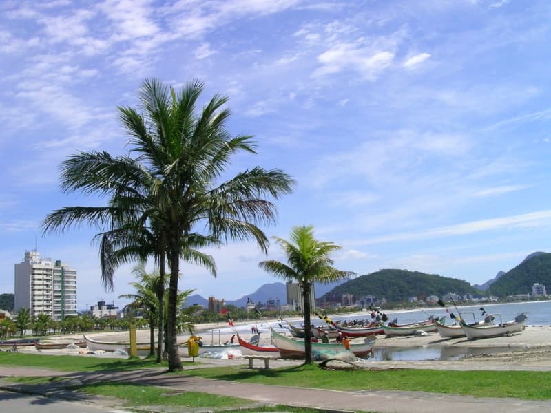 Orla do trapiche de Guaratuba com embarcações ancoradas e palmeiras à beira da baía