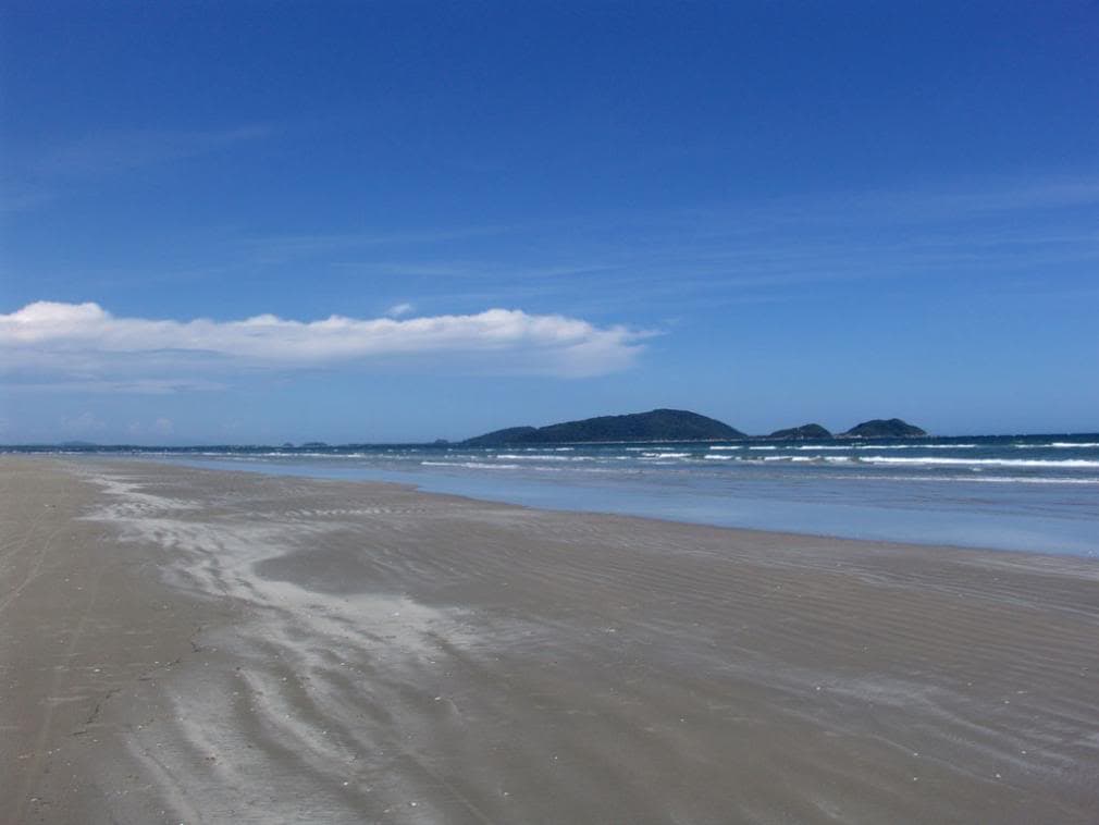 Balneário Ipanema com faixa de areia ampla e mar calmo sob céu azul