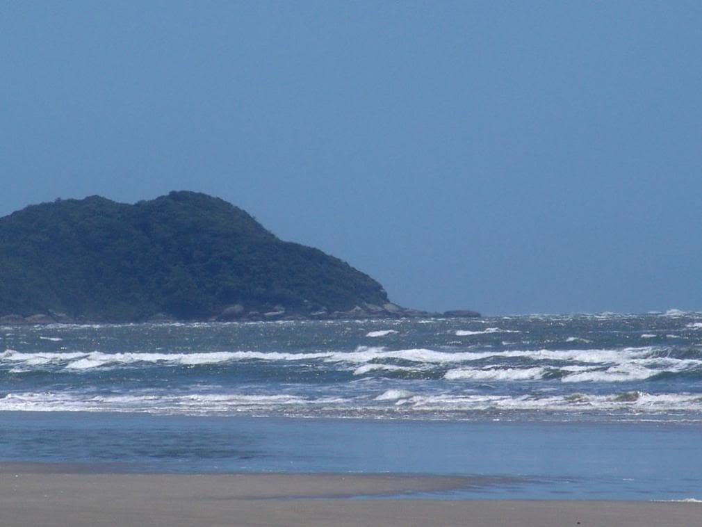Balneário Santa Terezinha com ondas no mar, areia dourada e morros ao fundo