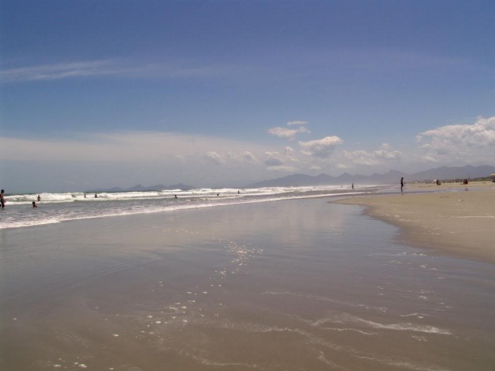 Balneário Shangri-lá com faixa de areia extensa e montanhas ao fundo